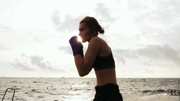 Closeup View of a Young Woman Shadow Boxing with Her Hands Wrapped in Purple Boxing Tapes By the Sea