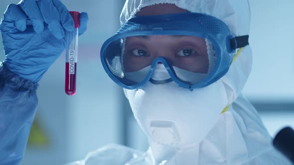 Female Asian Lab Scientist Holding Test Tube with Covid-19 Inscription