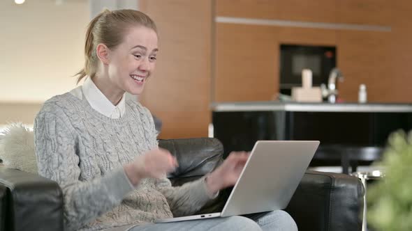 Young Woman Celebrating Success on Laptop at Home 