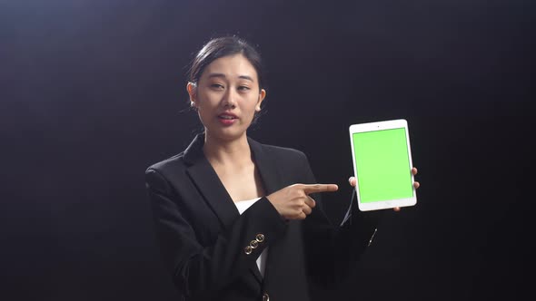 Asian Speaker Woman Holding And Pointing Green Screen Tablet While Speaking On Stage