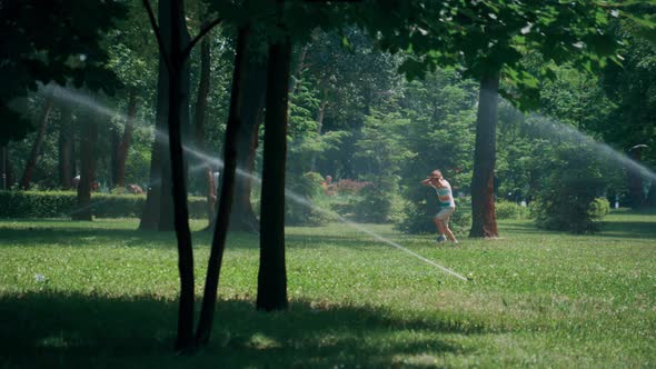 Playful Little Boy Running Water Sprinkles in Green Park Hiding Ears From Splash