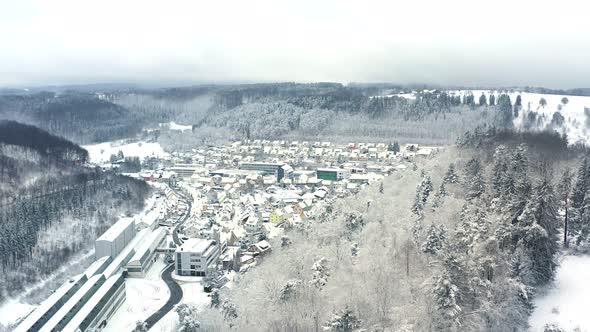 Smooth flight straight forward over a winter landscape. A snowy city is discovering behind a hill fu