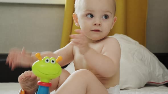 Toddler Playing with Plastic Toy Sitting on Bed