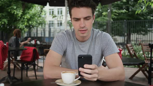 Man Using Smartphone While Sitting in Cafe Terrace