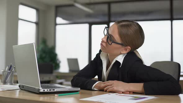 Young Woman Bored Working at Computer in Office Exhausted and Unmotivated