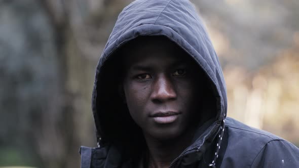 Confident serious hooded black african man staring at camera in the park