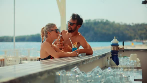 Couple On Bar Counter Relaxing. Lovers On Bar Counter Drinking Cocktails.Couple Honeymoon