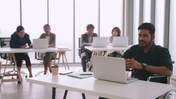 A disabled company employee is able to work happily with colleagues in the office.