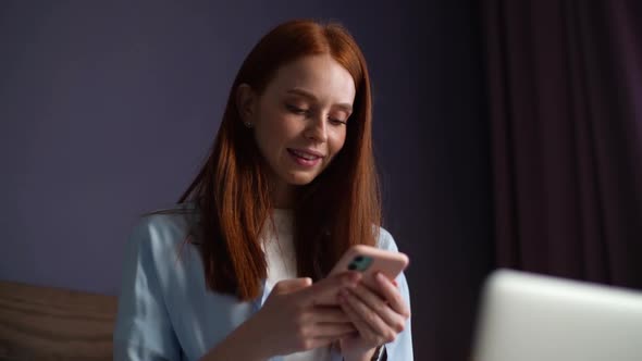 Close-up Face of Attractive Young Woman Typing Message on Mobile Phone at Bedroom