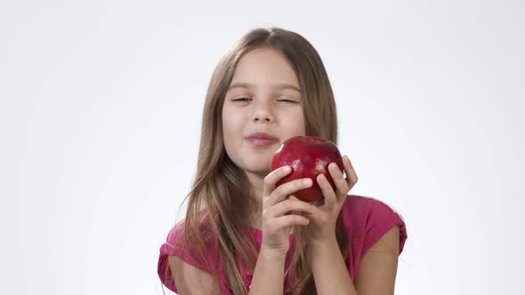 Little Girl on White Eats a Big Red Apple. A Girl Bites a Piece of Red Ash and Tastes It.