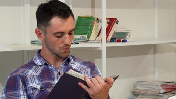 Handsome Young Man Smiling Joyfully While Reading a Book