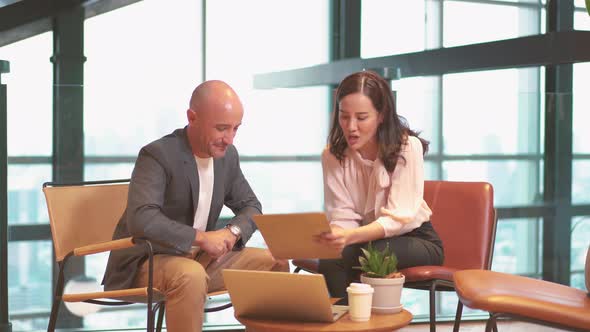 Asian female financial agent consulting caucasian male client customer explaining insurance contract