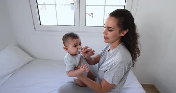 Young mother having fun with her baby on bed at home