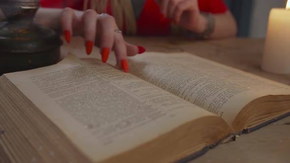 Female Hand Runs Finger Under Words on Spellbook