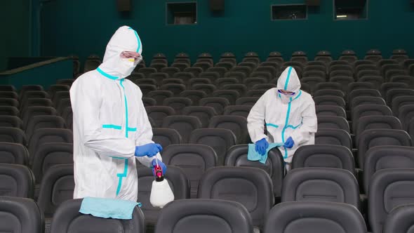 Two Workers Wiping Chairs with Disinfectants in Cinema