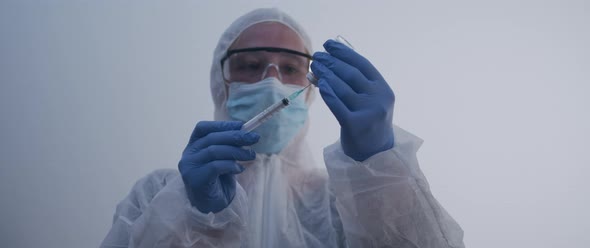 Woman holding up a syringe extracting fluid from bottle slow motion