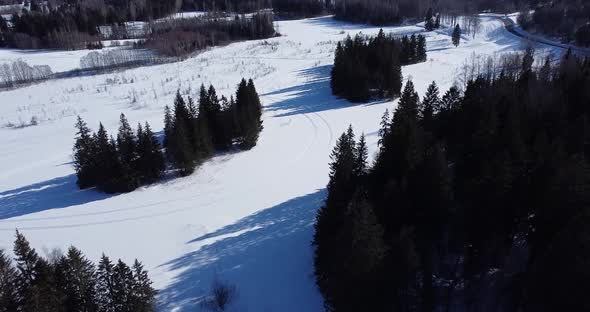 Flying Over Frozen Lake Surrounded By Shadows From the Trees