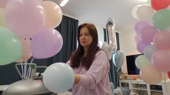 Woman Using Helium Tank Blowing Up Balloons to Decorate Home for Party Colorful Balloons for