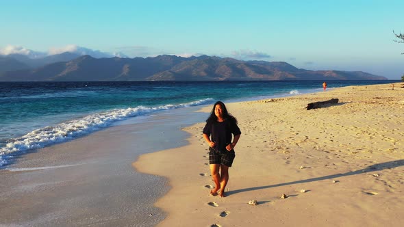 Beautiful happy lady travelling by the sea at the beach on sunny blue and white sand 4K background