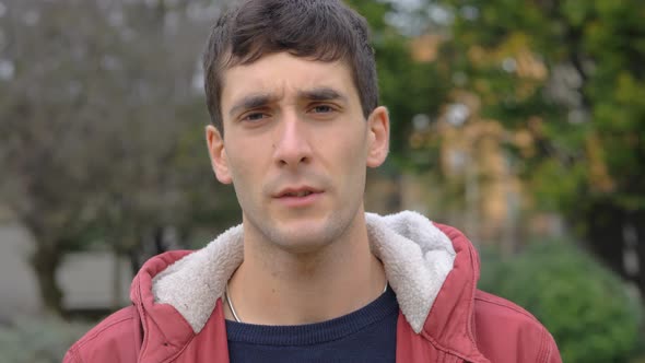 Confident attractive young caucasian man looking at camera in the park