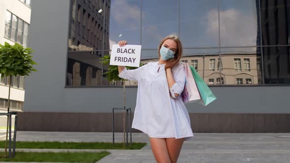 Girl in Protective Mask with Shopping Bags Showing Black Friday Inscription During Coronavirus