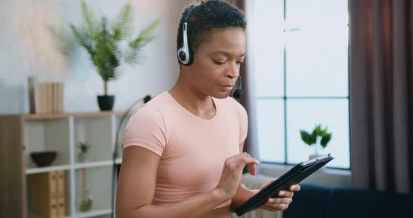 Woman in Headset which Working on Tablet Device while Stepping on Running Machine