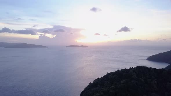 Aerial view of bright sunrise and small clouds on blue sky above seascape with islands in Asia