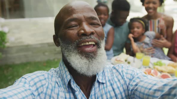 Portrait of happy african american family taking selfie and having breakfast in garden