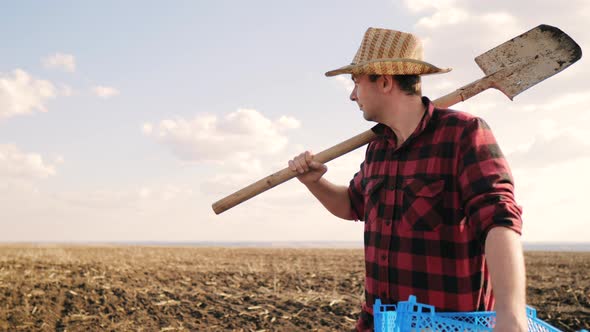 Farmer Digging Soil with Shovel in Rubber Boots in Garden Field at Sunset Spring