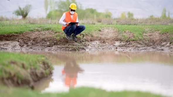 Engineer Taking Notes on Water Canal Used for Agriculture