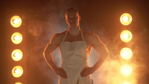 Portrait of Muscular Chef Wearing White Apron and Chef Hat on Smoky Background