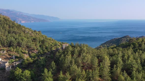 wide aerial view of whats left of the abandoned Kayakoy village with one last building on top of a h