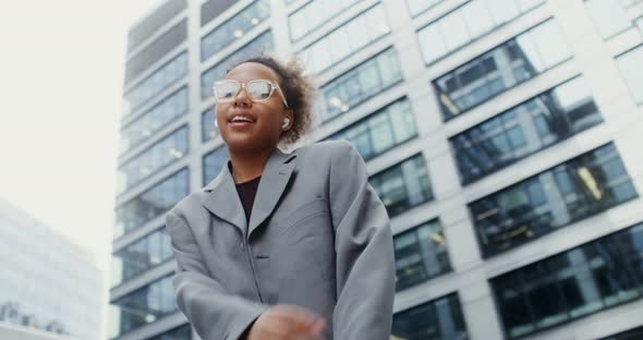 A Woman Wearing Headphones Listens to Music and Dances Outside Office Building