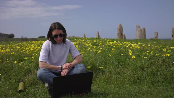 The Girl Works at the Laptop Sitting on the Green Grass