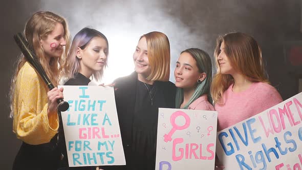 Group of Young Caucasian Feminists with Posters Stand Laughing and Smiling Isolated in Smoky Space