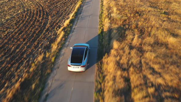 Aerial Shot of Electrical Car Driving on Country Road at Sunny Day