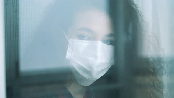 Woman's Face in a Protection Mask Shot Through the Window