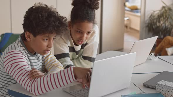 Afro-American Siblings Playing on Laptop in Classroom