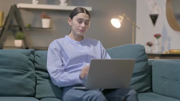 Hispanic Woman with Laptop having Neck Pain on Sofa