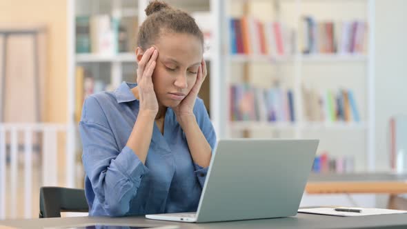 Stressed African Woman with Laptop Having Headache in Library