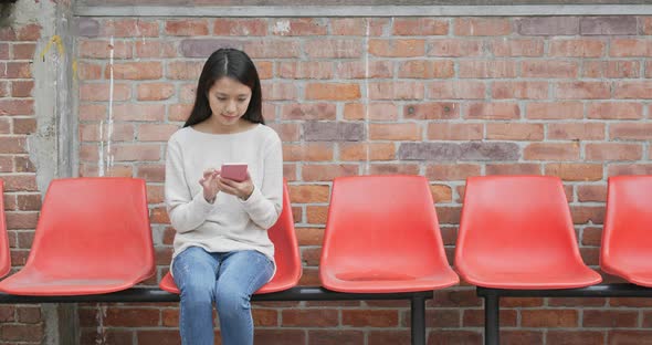 Woman use of smart phone over red brick wall