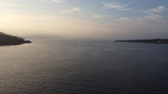 Approaching lonely sailboat in beautiful sunset at sotra Norway - Aerial showing sailing boat enjoyi