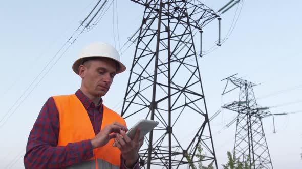 Engineer Inspects a Power Line Using Data From Electric Sensors on a Tablet