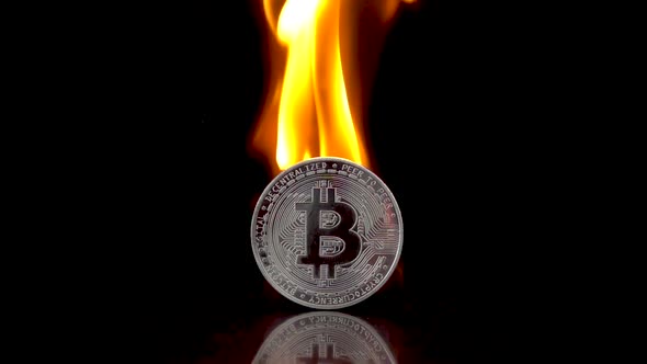 Silver Bitcoin Coin Catches Fire on an Isolated Black Background