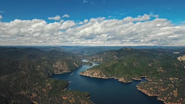 Bird's eye view drone shot of soft fluffy clouds looming over Pactola Lake, Wyoming, USA