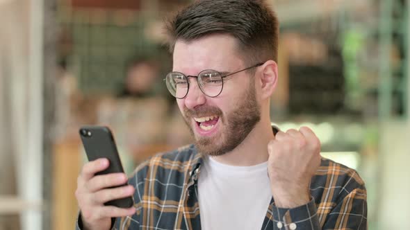 Portrait of Excited Young Man Celebrating on Smartphone 