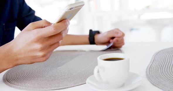 Man in lunch bar with smartphone and coffee