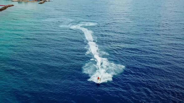 Dolly out aerial view of a person on a jet ski on the shores of Mambo Beach in Curacao, Dutch Caribb