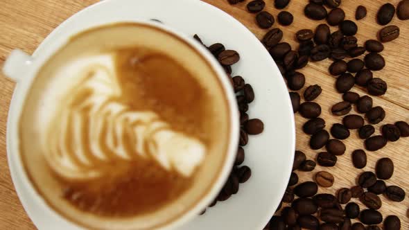 Close-up of coffee cup with saucer and coffee beans