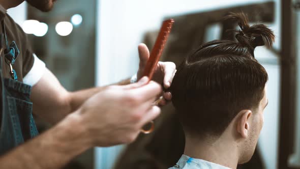 Barber makes a haircut to the client. Scissor cutting.